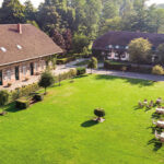 Drohnenaufnahme vom Linslerhof mit Hauptgebäude und Hotelwiese